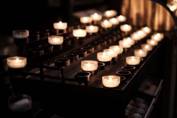 Rows of burning candles casting a warm glow in a Cologne chapel, Germany.